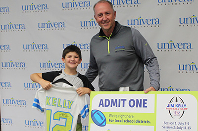 child holding a Jim Kelly shirt next to Paul Valley, President of Univera Healthcare