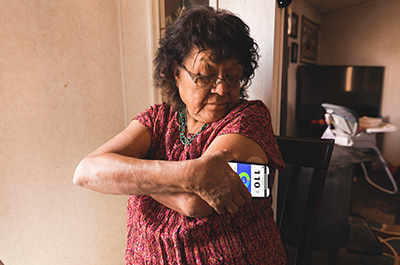 Older woman checking her blood sugar level with a cell phone